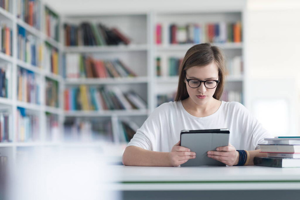 estudante do sexo feminino estuda na biblioteca da escola, usando tablet
 - Foto, Imagem