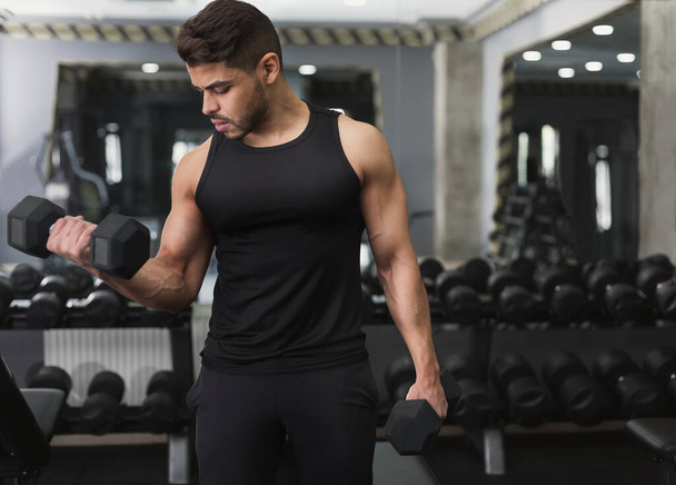 Arab man training with dumbbell in modern gym - Photo, Image