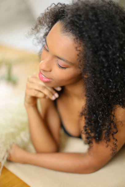 "Молодая черная женщина лежит опираясь на локти и носить бюстгальтер." - Фото, изображение