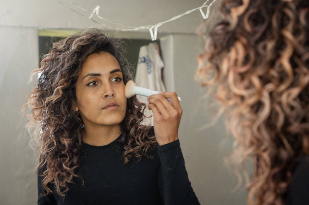 Rear view of woman applying makeup in mirror - Foto, imagen