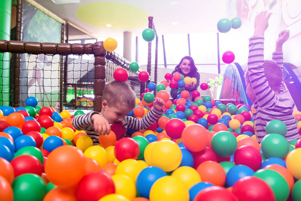Genç anne renkli toplarla bilardoda çocuklarla oynuyor. - Fotoğraf, Görsel