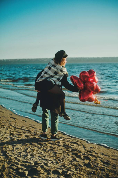 Happy running couple with a red heart balloons on the beach - Valokuva, kuva