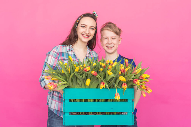 Family portrait sister and teenager brother with tulips on pink background - Photo, Image