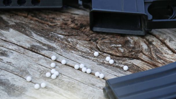Close up plastic bullets of airsoft gun or bb gun on wooden floor, soft and selective focus on the bullets - Photo, Image