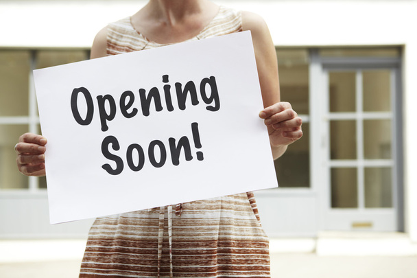 Woman Standing Outside Empty Shop Holding Opening Soon Sign - Foto, immagini