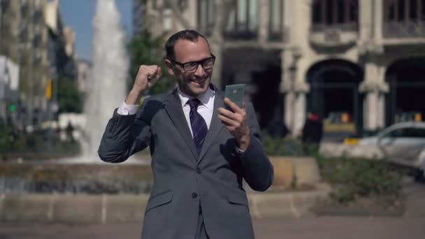 Successful businessman gets great news on smartphone - Imágenes, Vídeo