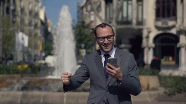 Successful businessman gets great news on smartphone - Imágenes, Vídeo