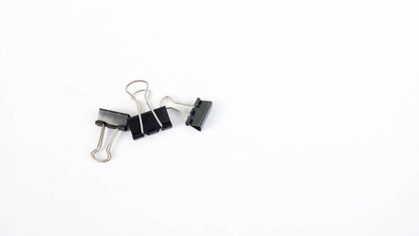 A binder clip is a strip of spring steel bent into the shape of an isosceles triangle with loops at the apex. This tool is used to clamp paper to make it neater. - Фото, изображение