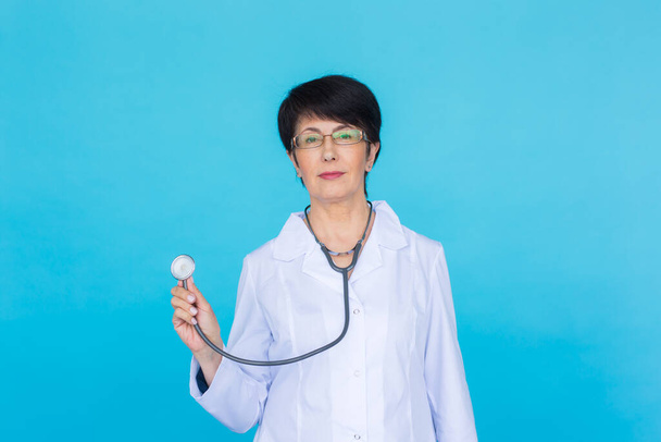 Una doctora con un estetoscopio escuchando, aislada sobre fondo azul
 - Foto, imagen