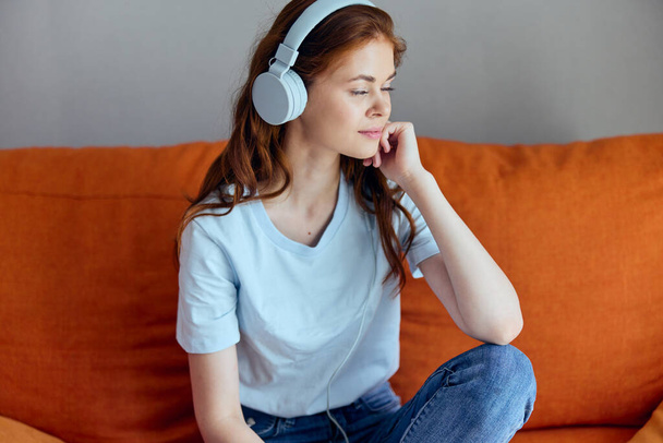 "beautiful woman sitting on the couch at home listening to music on headphones technologies" - Photo, Image