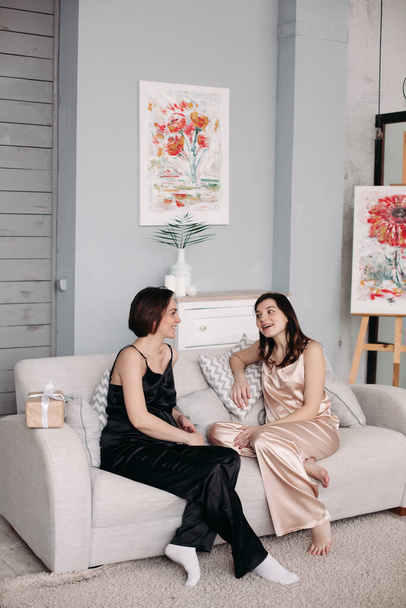 zwei junge Schwestern sitzen zu Hause auf dem Sofa und reden - Foto, Bild