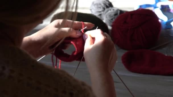 Žena ruce pletení ponožky s jehlicemi a příze červené barvy. Detailní záběr rukou - Záběry, video