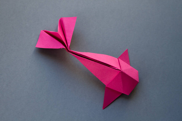 Pembe kağıttan balık origamisi boş gri bir arkaplanda izole edilmiş. - Fotoğraf, Görsel