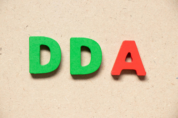Цветная буква алфавита в слове DDA (аббревиатура амортизации, истощения и амортизации или депозитного счета) на деревянном фоне - Фото, изображение