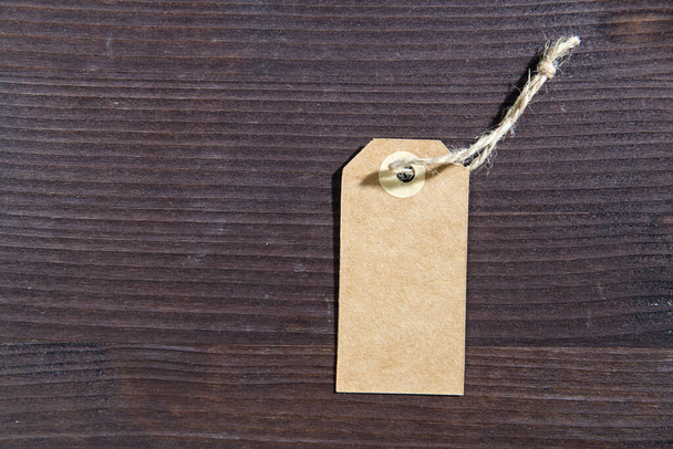Étiquette blanche vierge avec ficelle sur fond brun en bois. Espace de copie - Photo, image
