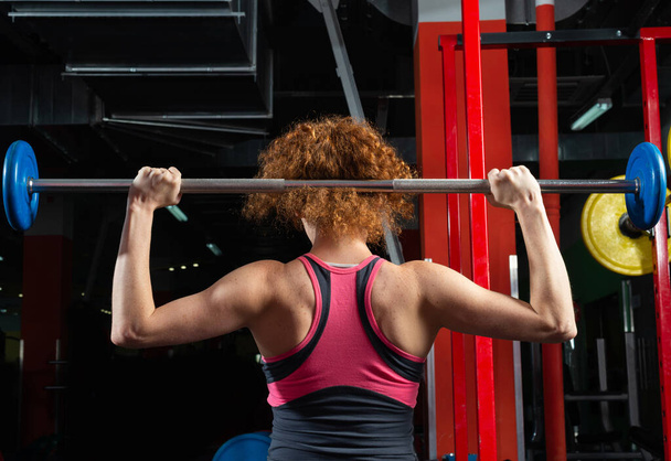 "Γυναίκα bodybuilder ασχολούνται με ένα barbell στο γυμναστήριο" - Φωτογραφία, εικόνα