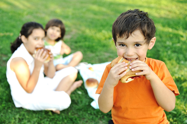 Piccolo gruppo di bambini in natura mangiare spuntini insieme, panini, pane
 - Foto, immagini