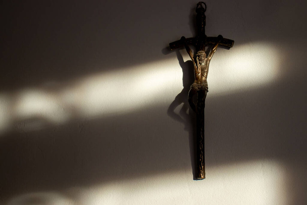 Metal cross with Jesus Christ. Crucifix of Jesus Christ on white wall in catholic family home. Christian background with copy space. Religion, belief and hope. - Photo, Image