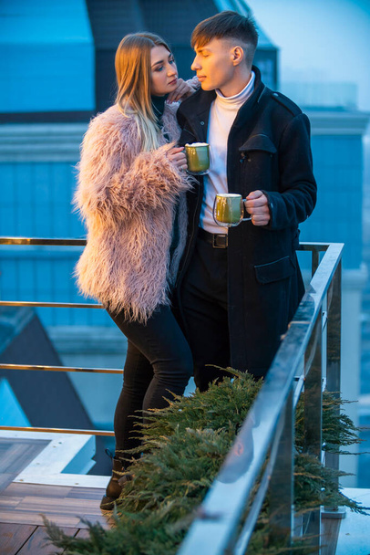 couple avec tasses sur la terrasse d'un immeuble de grande hauteur - Photo, image