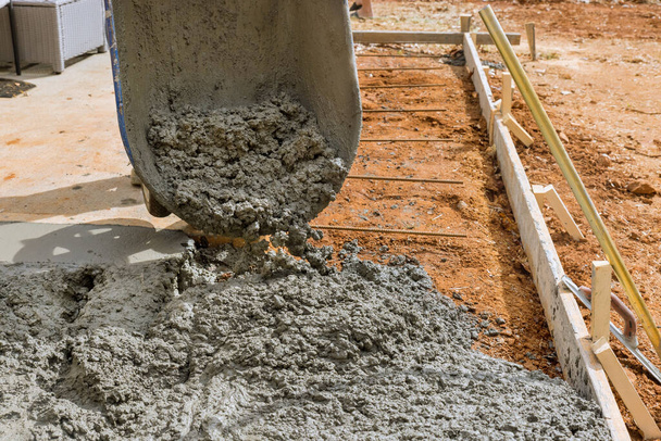 Будівельні підрядники заливають мокрий бетон під час мощення проїжджої частини під час роботи над бетонним будівельним проектом
 - Фото, зображення