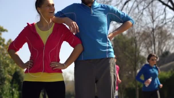 Happy sporty joggers, couple standing in park - Filmati, video