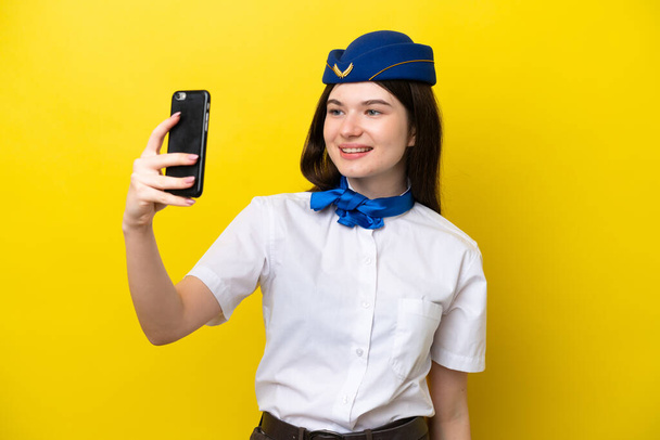 stewardessa samolotu Rosjanka odizolowana na żółtym tle robi selfie - Zdjęcie, obraz