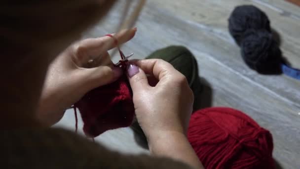 Žena ruce pletení ponožky s jehlicemi a příze červené barvy. Detailní záběr rukou - Záběry, video