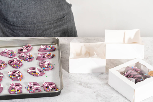 Packaging homemade mermaid pretzel twists into a white paper box. - Foto, afbeelding