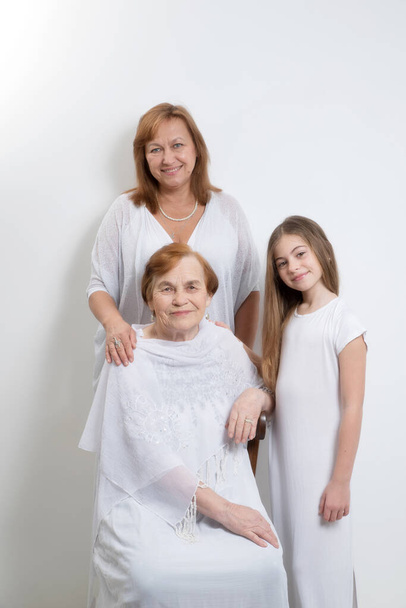 Eri sukupolvien ja ikäisten samaan perheeseen kuuluvien naisten muotokuva valkoisissa vaatteissa. - Valokuva, kuva