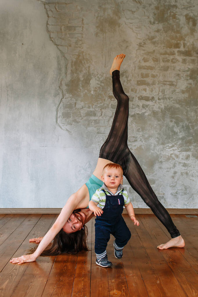 "A yoga girl performs an exercise, while her little son runs around" - Foto, imagen