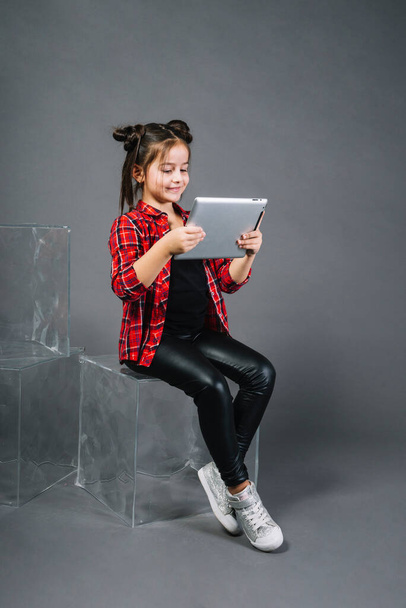 "μικρό κορίτσι κάθεται μπλοκ αναζητούν ψηφιακή ταμπλέτα σε γκρι φόντο" - Φωτογραφία, εικόνα