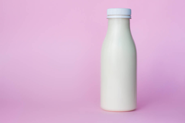 "Eine Flasche weiße Milch, hervorgehoben auf rosa Hintergrund, Nahaufnahme. " - Foto, Bild