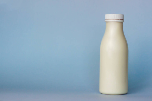 A bottle of white milk, highlighted on a blue background, close-up - Photo, Image