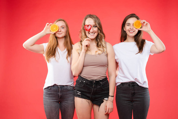 Τρία ευτυχισμένα κορίτσια με πορτοκάλια και γλυκά γλυκά. - Φωτογραφία, εικόνα