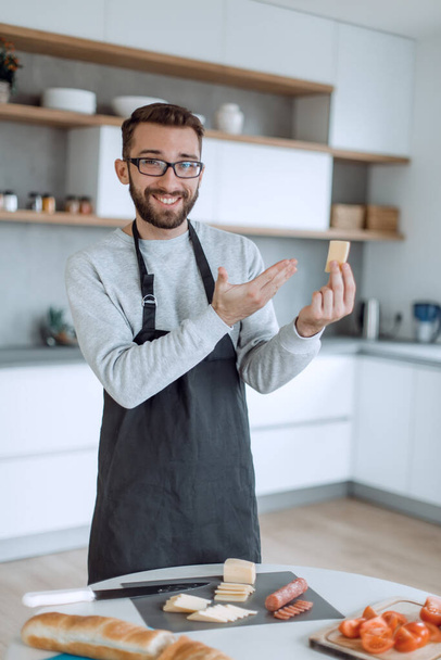 "Çekici bir adam lezzetli bir parça peynir gösteriyor." - Fotoğraf, Görsel