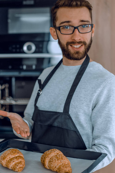 "smiling man holding a tray of fresh croissants" - Φωτογραφία, εικόνα