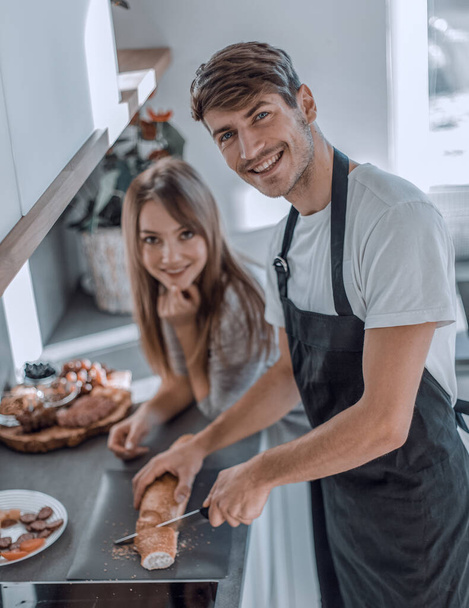 "happy young couple with food in their new kitchen - Foto, imagen