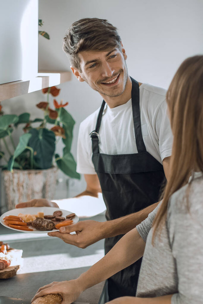 "feliz pareja joven con comida en su nueva cocina - Foto, imagen