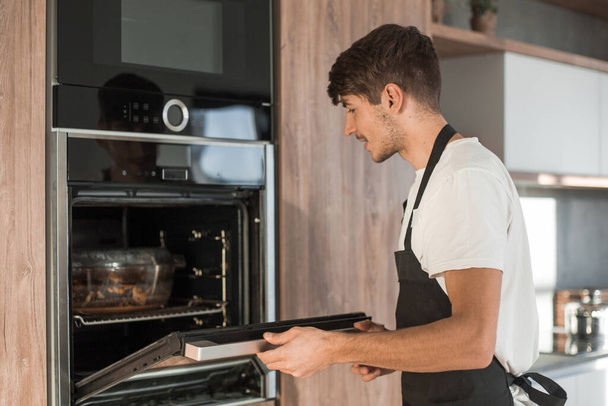 "hombre abriendo el horno en la cocina del hogar
" - Foto, Imagen