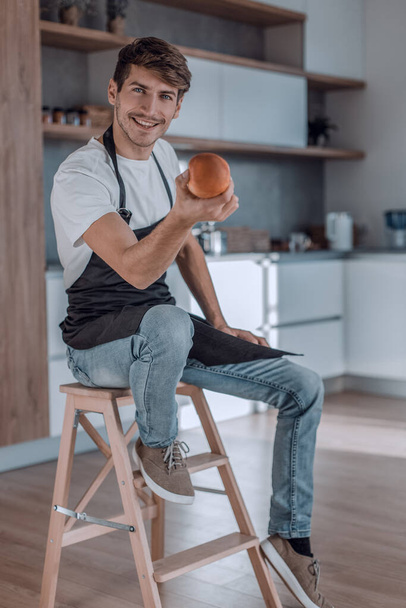 "attractive man with an apple sitting in a home kitchen" - Valokuva, kuva