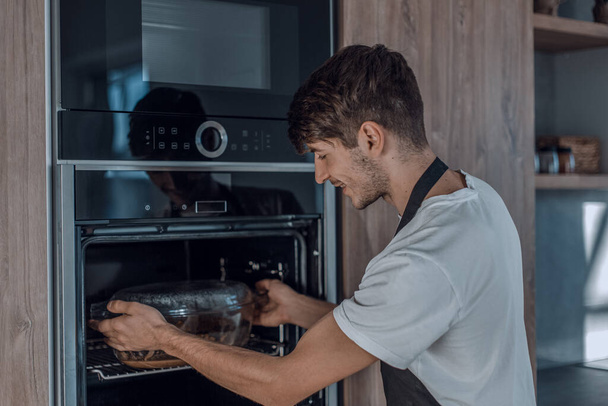 "jonge man opwarmen diner in de oven" - Foto, afbeelding