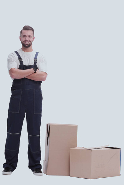 "serious man in overalls standing near the boxes. isolated on white" - Fotografie, Obrázek