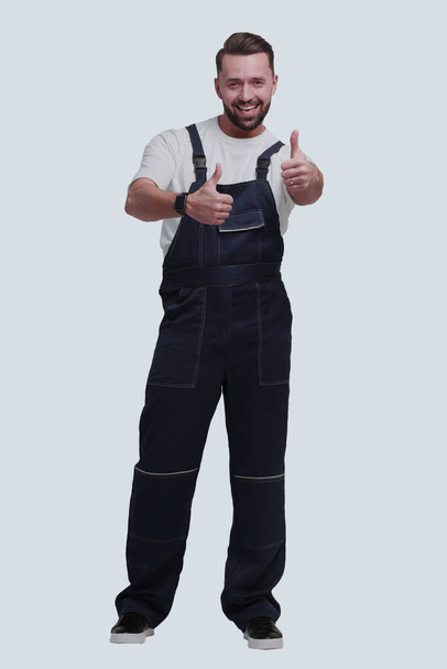 "in full growth. friendly man in overalls showing thumbs up" - Foto, imagen