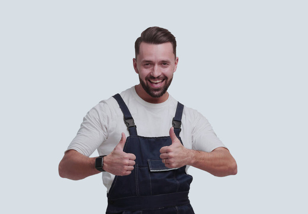 "in full growth. friendly man in overalls showing thumbs up" - Valokuva, kuva