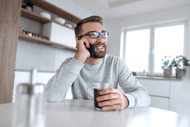 aantrekkelijke man praten op zijn smartphone tijdens het ontbijt - Foto, afbeelding