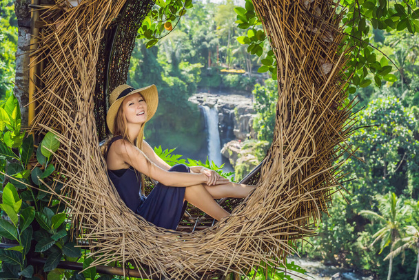 "Bali trend, gniazda słomy wszędzie. Młody turysta ciesząc się jej podróży wokół wyspy Bali, Indonezja. Przystanek na pięknym wzgórzu. Zdjęcie w gnieździe słomy, środowisko naturalne. Stylu życia" - Zdjęcie, obraz