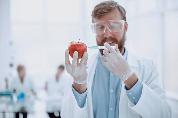 experto con Apple y jeringa de pie en el laboratorio - Foto, Imagen