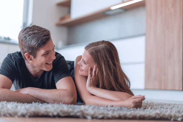 gelukkig jong paar liggend op het tapijt in hun nieuwe appartement - Foto, afbeelding