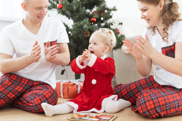 Toddler child with cochlear implant plays with parents under Christmas tree - deafness and innovating medical technologies for hearing aid - 写真・画像