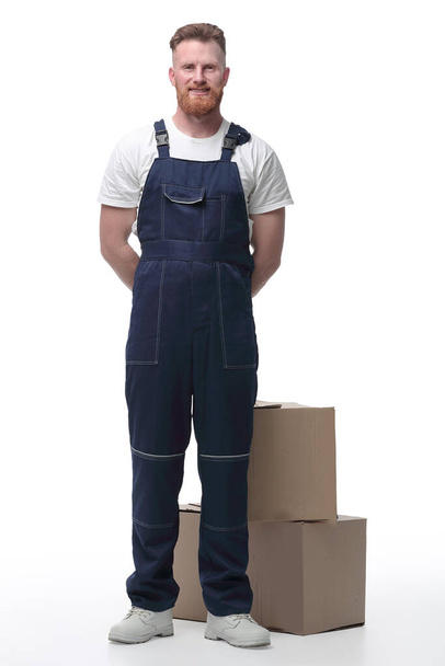 "friendly man in overalls standing near cardboard boxes" - Foto, afbeelding